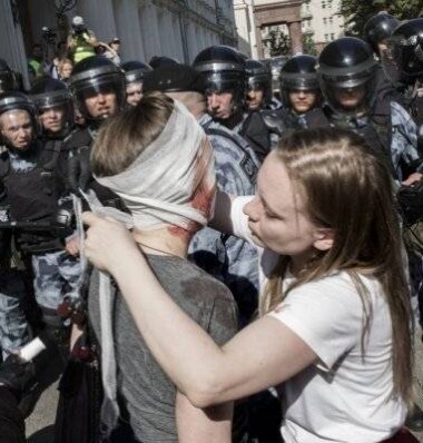 Муниципальному депутату Александре Петушиной перевязывают голову. Она получила травму во время столкновений с полиции с протестующими / Фото Анны Артемьевой из галереи «Новой Газеты»